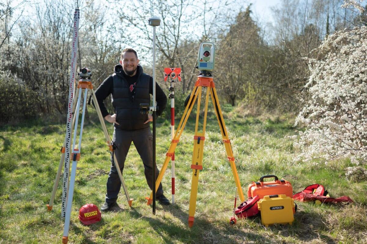 Geodeta Tomasz Kępka ze sprzętem pomiarowym - niwelator, GNSS, tachimetr