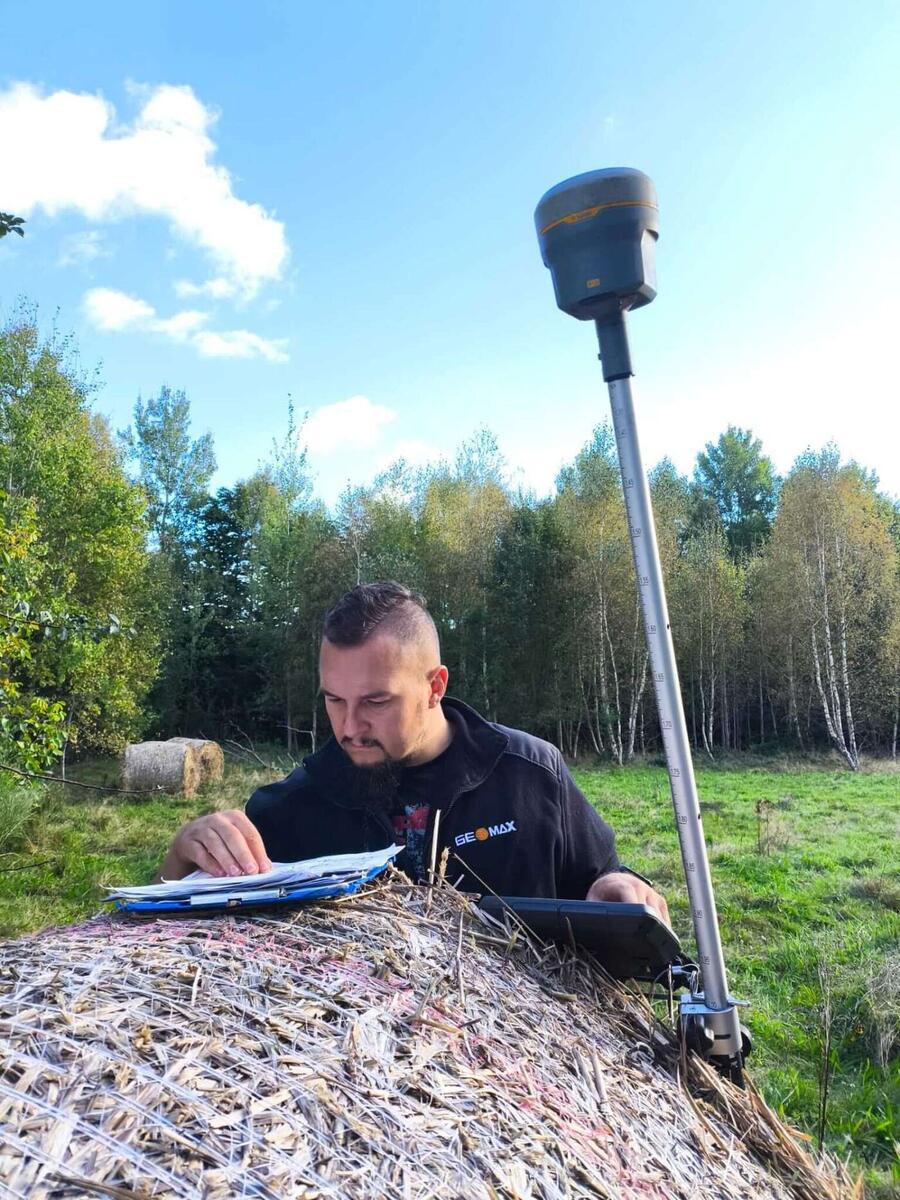 Geodeta analizujący dokumentację podczas pomiarów GNSS w terenie