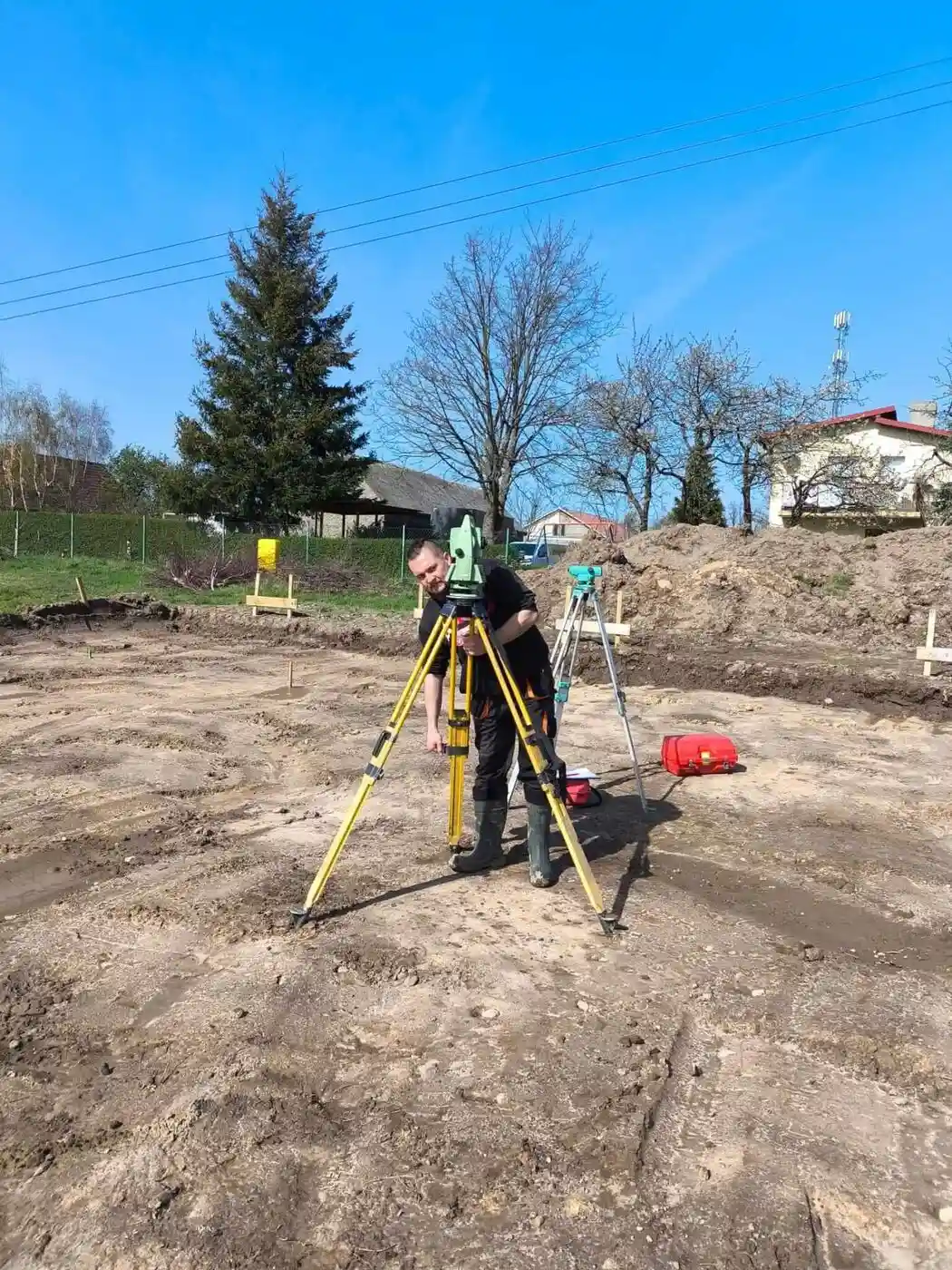 Geodeta wykonujący tyczenie budynku tachymetrem na placu budowy